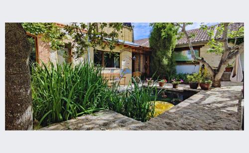 una casa con un estanque en el patio en Viento de Ladera PISCINA NATURAL y JACUZZI EXT en Segovia