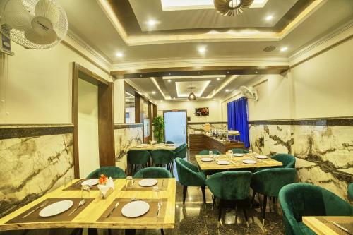 a restaurant with wooden tables and green chairs at SM Royal Suites - Hotel near Kempegowda international Airport Bangalore in Devanahalli-Bangalore