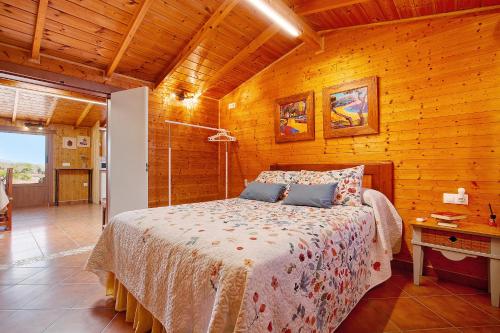 1 dormitorio con 1 cama y pared de madera en La Casita de Vidal en Tuineje