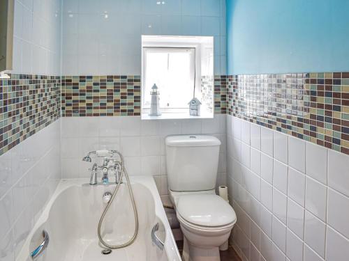 La salle de bains est pourvue de toilettes et d'une baignoire. dans l'établissement Tyn Y Berth, à Talsarnau