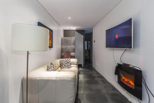 ein Wohnzimmer mit einem weißen Sofa und einem TV in der Unterkunft Hostel & cia in Porto