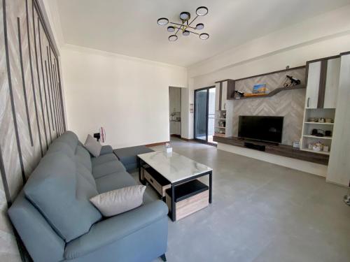 a living room with a blue couch and a tv at Muchen BnB in Magong