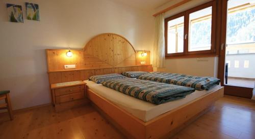 a bedroom with a large bed with a wooden headboard at Apartments Antersi Claudia in San Vigilio Di Marebbe