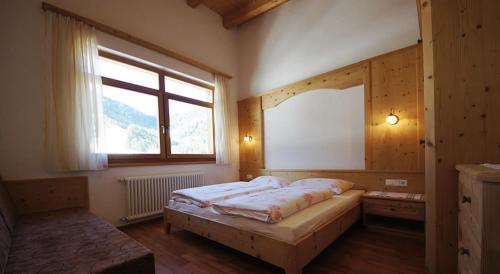 a bedroom with a large bed and a window at Apartments Antersi Robbi in San Vigilio Di Marebbe