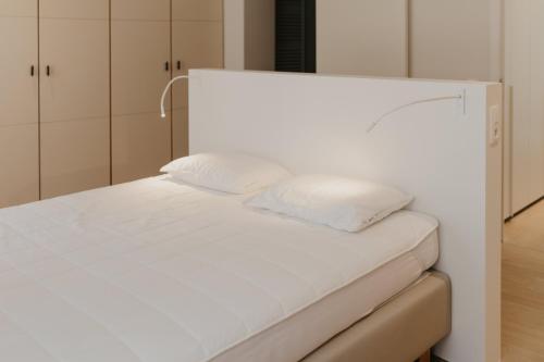 a white bed with two pillows on top of it at Blue Bird Residence Moriaan in Antwerp