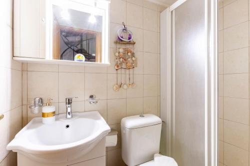 a bathroom with a sink and a toilet and a mirror at Sea view maisonette near Nafplio!1' drive to beach in Kivérion