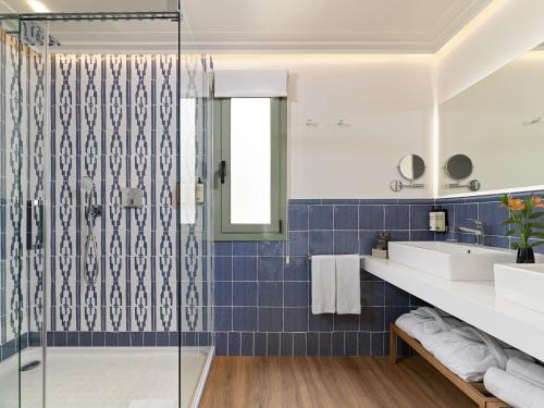 y baño con azulejos azules y ducha. en H10 Universitat, en Barcelona