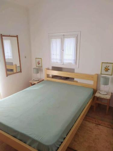a large bed in a room with two windows at Beautiful Cottage over-viewing Samos bay. in Samos