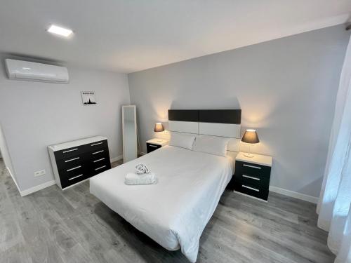 1 dormitorio con 1 cama blanca y 2 mesitas de noche en D.A.U. Centro Parking Opcional, en Salamanca