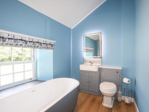 uma casa de banho azul com uma banheira, um WC e um lavatório. em The Forge em Holyhead