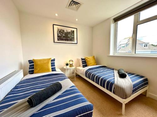 two beds in a room with a window at Stunning Panoramic Sea View Beach Location - Sleeps up to 4 People - Free Parking - The Best Beach! - Great Location - Fast WiFi - Smart TV - Newly decorated - sleeps up to 4! Close to Bournemouth & Poole Town Centre & Sandbanks in Bournemouth