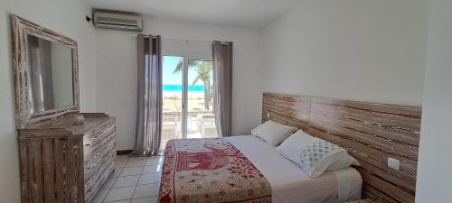 a bedroom with a bed and a mirror and a window at Beach House sol y mar #17 in Rabil