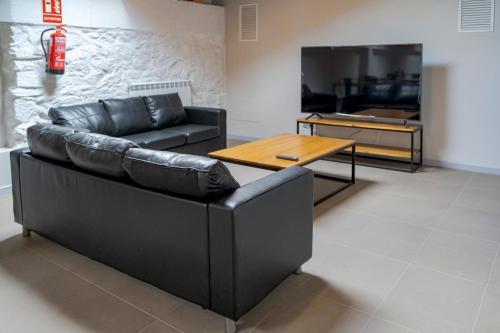 sala de estar con sofá de cuero negro y mesa en Albergue de Cerceda, en Cerceda