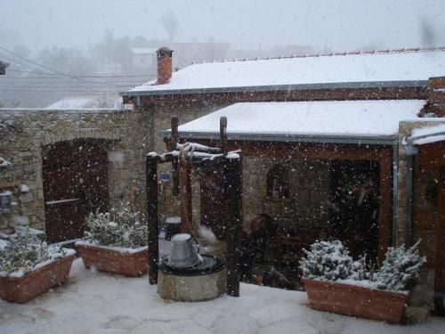 a snow covered yard with plants and a building at Xenios Cottages in Lofou