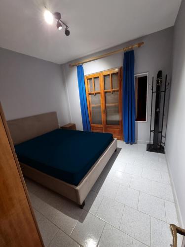 a bedroom with a bed with blue sheets and blue curtains at Meltemi Apartments in Asprovalta