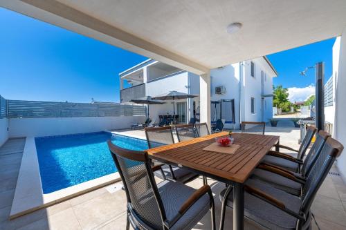 una mesa de madera y sillas en un patio con piscina en Villa Ema and Ana, en Pula