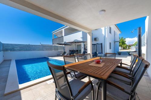 a wooden table and chairs on a patio with a pool at Villa Ema and Ana in Pula