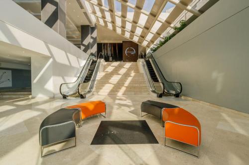a hallway with orange and black chairs in a building at Real Inn Tijuana by Camino Real Hoteles in Tijuana