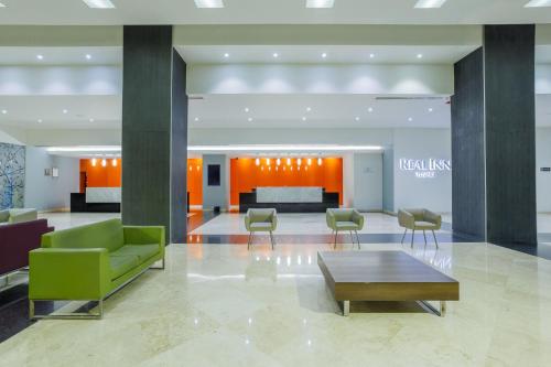 - un hall avec un canapé vert, des chaises et une table dans l'établissement Real Inn Tijuana by Camino Real Hoteles, à Tijuana