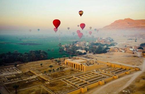 a group of hot air balloons flying over a temple at Nile diana luxor in Luxor