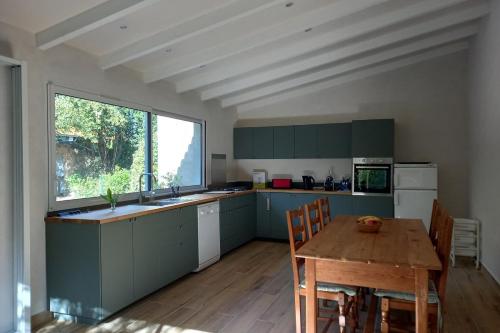 une cuisine avec des placards verts et une table en bois dans l'établissement L Oustal maison vigneronne, à Villeneuve-lès-Béziers