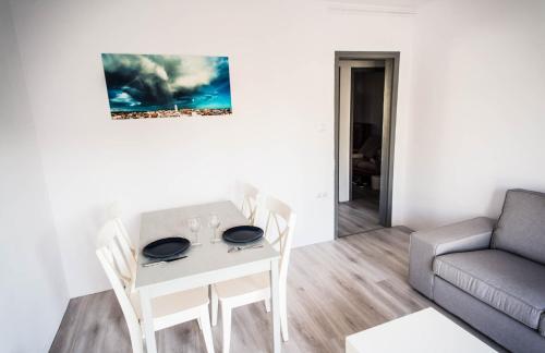 een woonkamer met een tafel en stoelen en een bank bij Beach Lovers' Paradise, bright apartment for 2/3 in Vilanova i la Geltrú