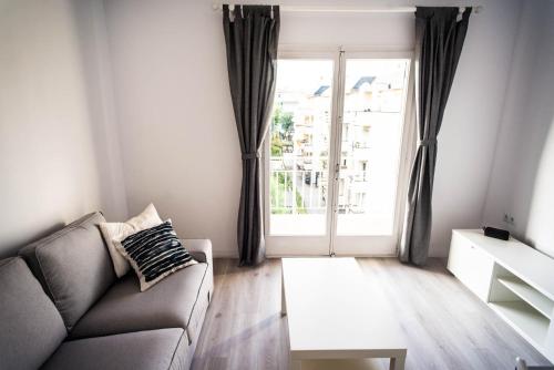 a living room with a couch and a large window at Beach Lovers' Paradise, bright apartment for 2/3 in Vilanova i la Geltrú