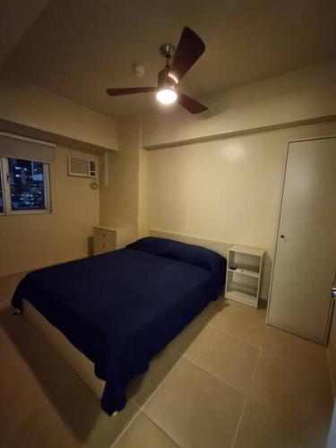 Schlafzimmer mit einem blauen Bett und einem Deckenventilator in der Unterkunft Live the BGC lifestyle! in Manila