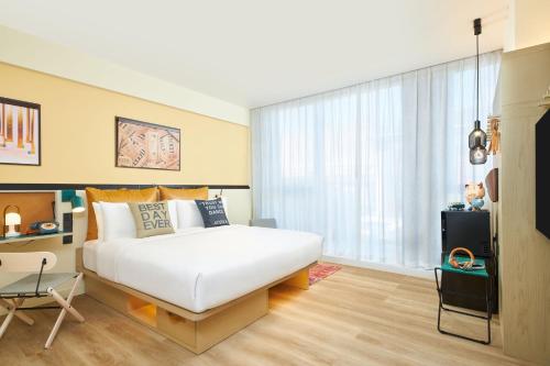 a bedroom with a white bed and a large window at Moxy Xi'an Downtown in Xi'an