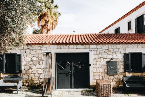 a stone house with a black door and a window at GAIA ALAÇATI in Alacati