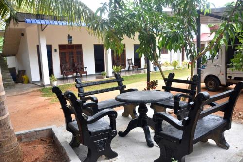 a group of benches and a table in front of a building at Wilpattu Lakwin Guest in Pahala Maragahawewa