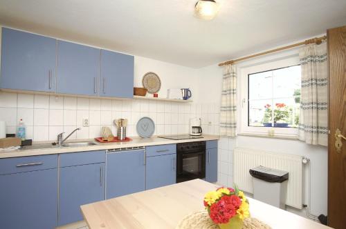 eine Küche mit blauen Schränken, einem Tisch und einem Fenster in der Unterkunft zentral aber ruhig, Terrasse mit viel Grün - strandnahes Ferienhaus Luki in Göhren