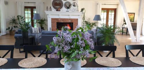a living room with a fireplace and a table with purple flowers at Majątek Morgi in Suchowola