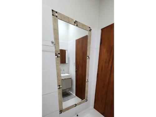 ein Badezimmer mit einem Spiegel und einer Holztür in der Unterkunft Casa Acerola - Vila de São Jorge in Sao Jorge
