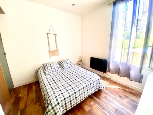 - une chambre dotée d'un lit avec une couverture tressée et une fenêtre dans l'établissement Grand T2 en rez de chaussée avec grande terrasse proche du centre ville tramway à 2 mn, à Nice