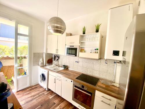 une cuisine avec des armoires blanches et un évier dans l'établissement Grand T2 en rez de chaussée avec grande terrasse proche du centre ville tramway à 2 mn, à Nice