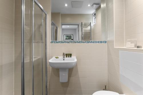 La salle de bains blanche est pourvue d'un lavabo et d'une douche. dans l'établissement Self-contained studio, à Londres