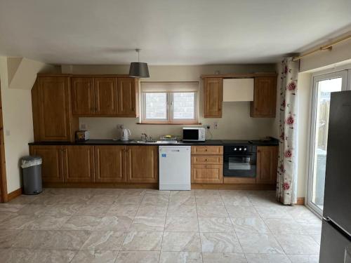 a kitchen with wooden cabinets and a white appliance at Modern 4 Bed House in town in Tobercurry