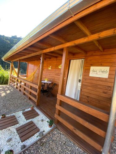 a wooden cabin with a porch with a sign on it at Cabana Amor Perfeito in Barracão