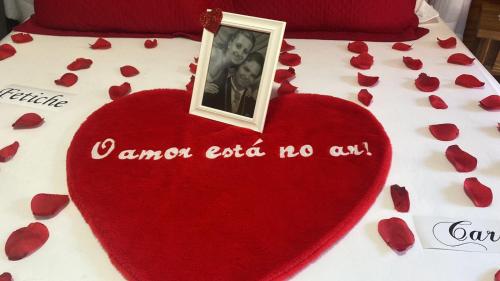 a heart with a picture on top of a bed with hearts at Cabana Amor Perfeito in Barracão