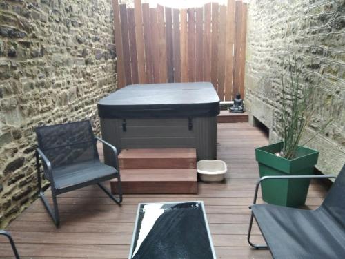 a patio with a bed and chairs and a table at Charmant logement avec jacuzzi in Fougères