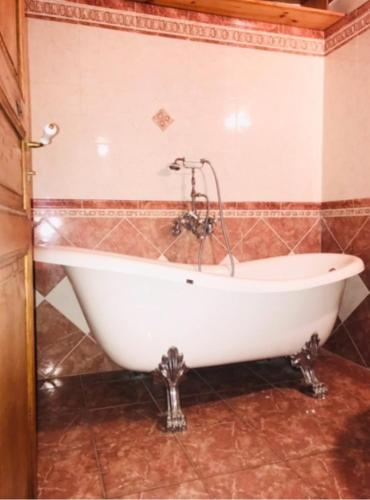 een witte badkuip in een badkamer met een betegelde muur bij La maisonnette in Le Nayrac