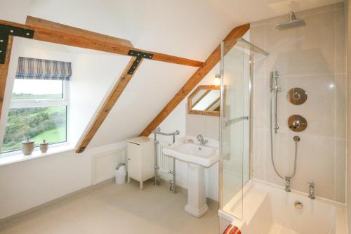 uma casa de banho com um chuveiro e um lavatório. em Overdene - Luxury House With Magnificent Sea Views em Tintagel