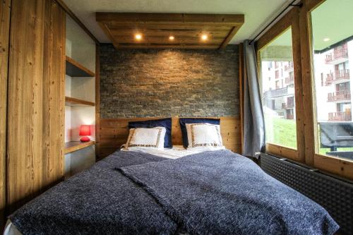 - une chambre avec un grand lit et un mur en briques dans l'établissement Très beau T2 idéalement situé Tignes Val Claret, à Tignes