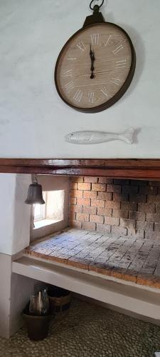 a clock on a wall above a brick wall at Casa Pescador Beach House in Struisbaai