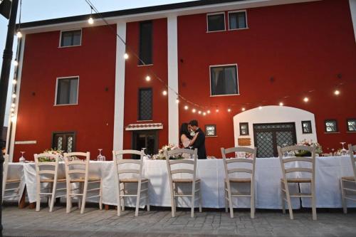 ein Paar steht an einem Tisch vor einem roten Gebäude in der Unterkunft Agriturismo La Caffettiera in Sparanise