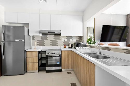 a kitchen with white cabinets and a stainless steel refrigerator at Luxurious 3BR Villa Amaranta in Dubai