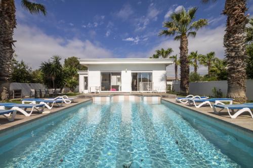 une piscine avec des chaises et une villa dans l'établissement Envie de Vivre, à Agde