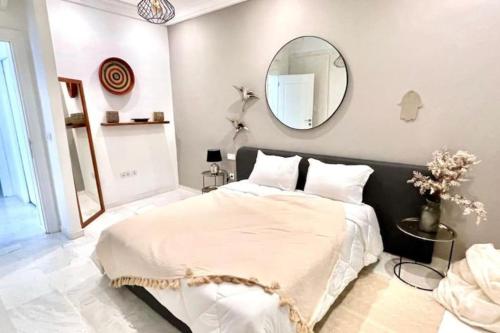 a bedroom with a large bed and a mirror at Capucines La Marsa plage in La Marsa