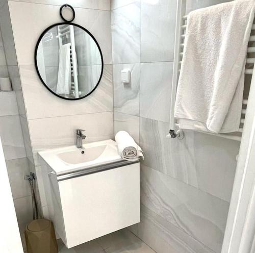 a white bathroom with a sink and a mirror at Capucines La Marsa plage in La Marsa